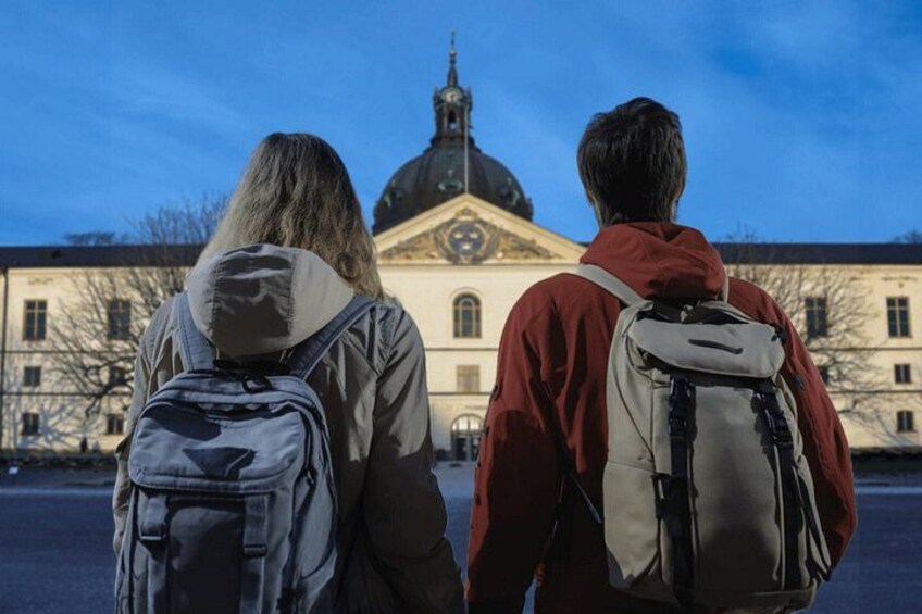 Dos personas con mochilas caminando hacia un edificio con cúpula y reloj. 3