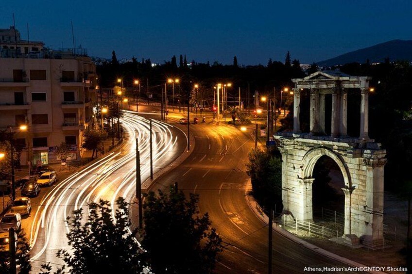 A nighttime cityscape with a roundabout, streetlights, and a classical arch structure. 5