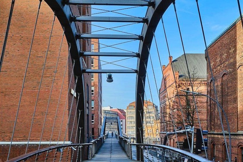 A pedestrian bridge with metal railings and a brick building on one side. 3