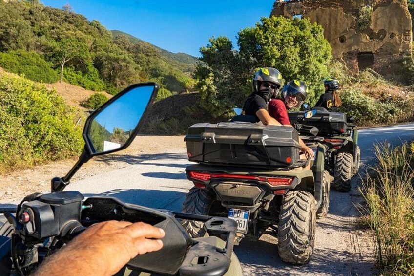 A dirt road with off-road vehicles, a person in the foreground, and a hilly landscape in the background. 5