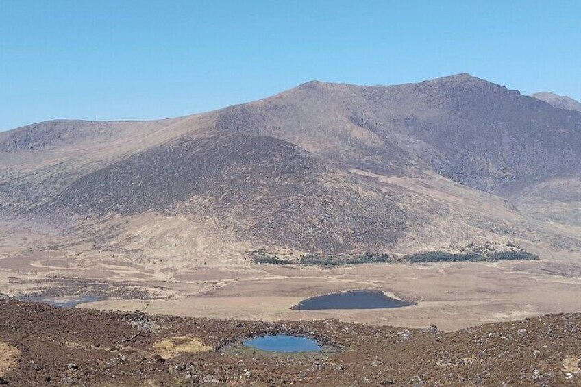 A mountainous landscape with a small lake in the foreground and a clear sky. 4