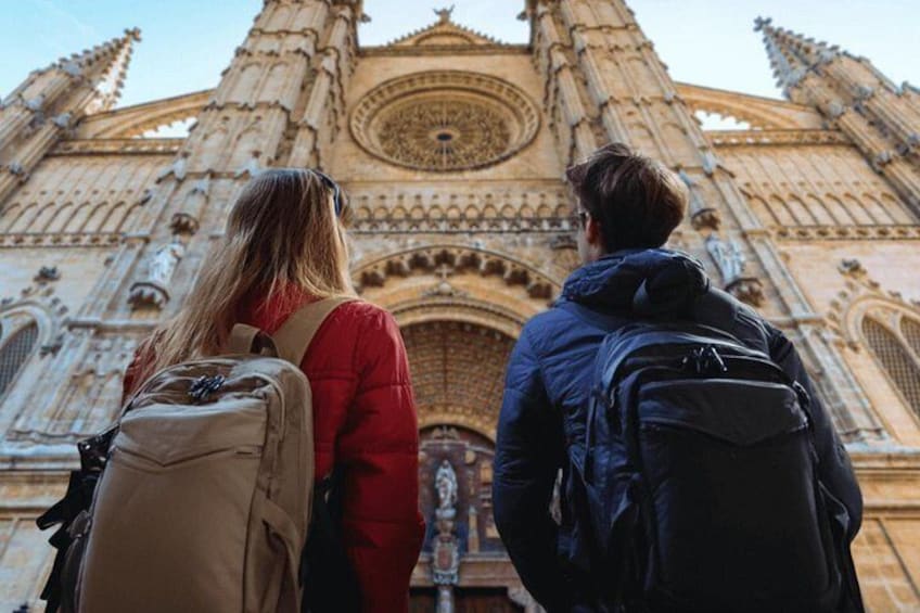 Two people standing in front of a large, ornate cathedral with intricate architectural details. 5
