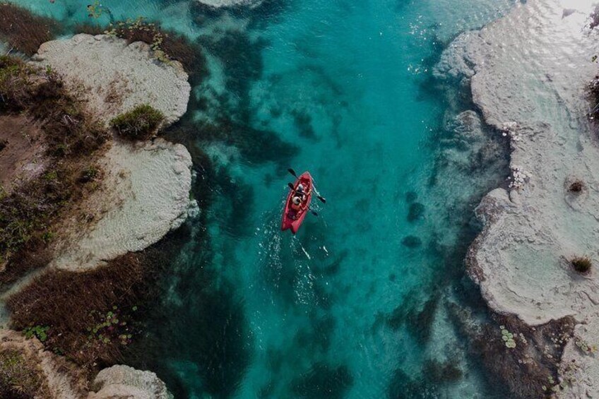 Een kajak op turquoise water, omringd door rotsformaties. 5