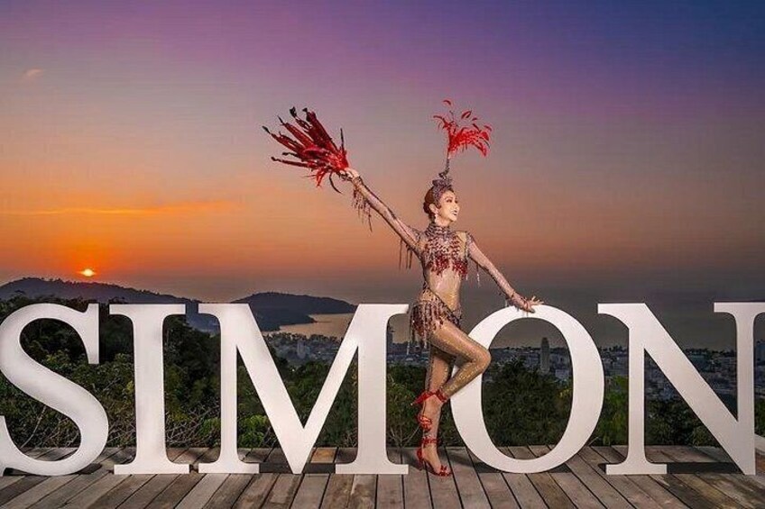 A person in a costume with feathers, standing in front of large letters spelling 'SIMON'. 5