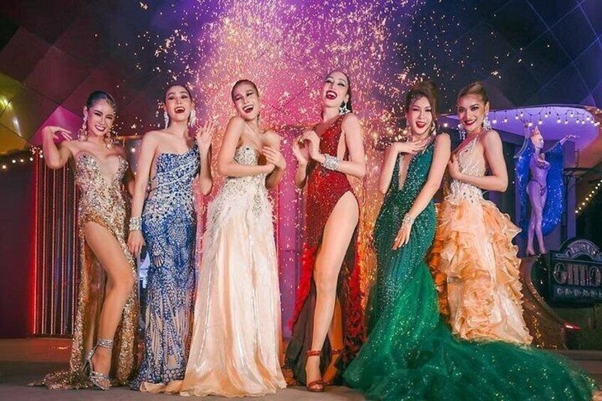 A group of women in formal dresses posing on a stage with a sparkling backdrop. 3