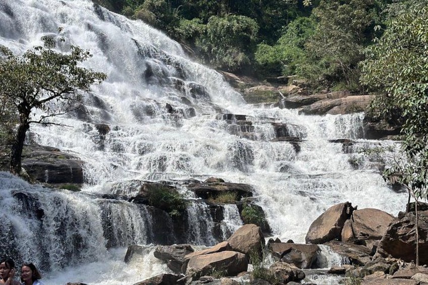Een meerlaagse waterval omringd door rotsen en bomen. 3