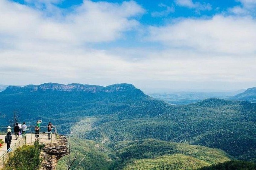 A mountainous landscape with a group of people standing on a viewing platform. 4