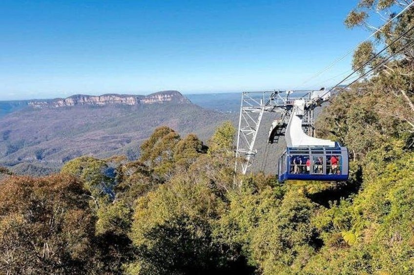 A cable car on a mountain ridge with a view of a distant mountain range. 2