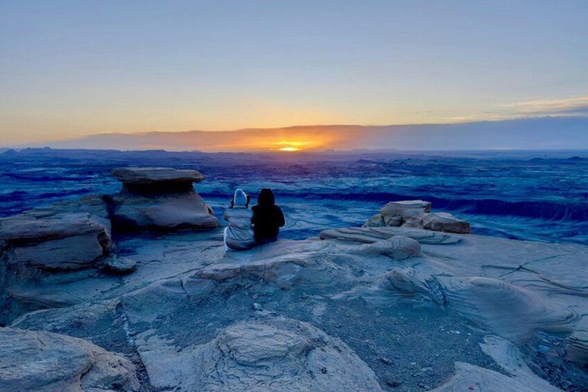 A person sitting on rocks by the sea during sunset. 2