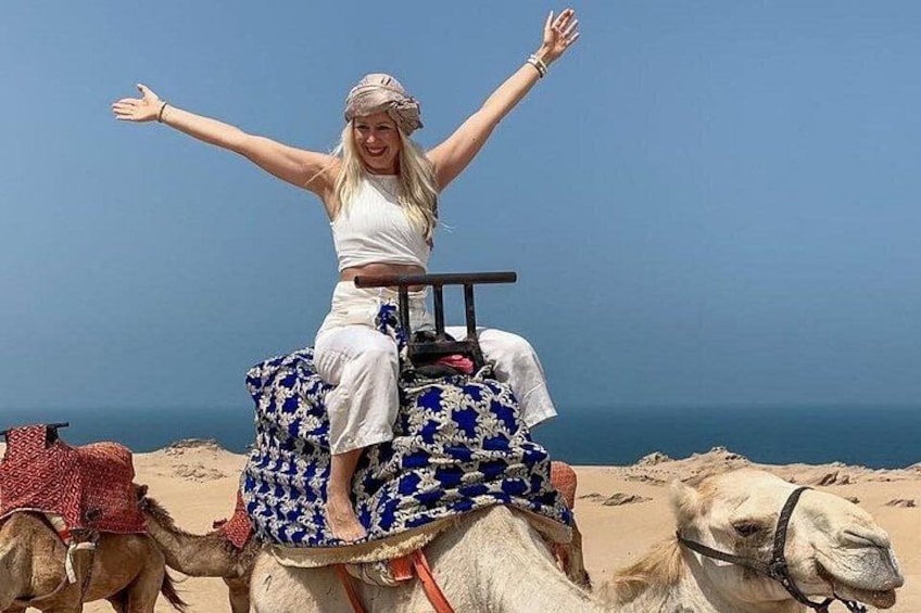 A person riding a camel on a beach with the sea in the background. 3