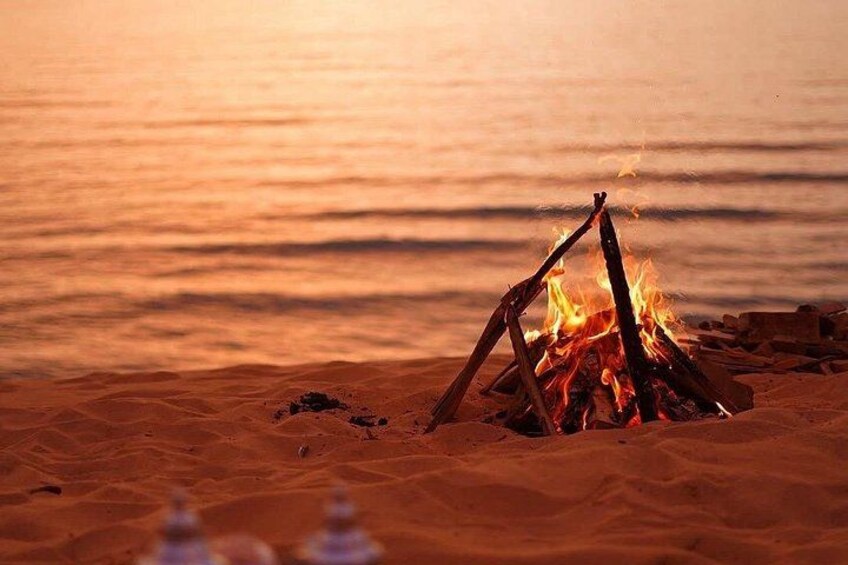 A campfire on a sandy beach with the ocean in the background. 2