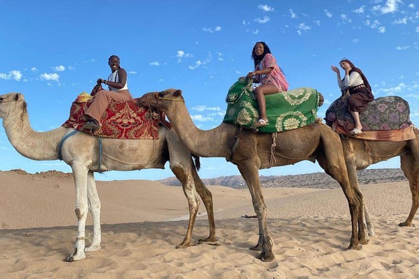 Three camels with riders in a desert landscape. 1