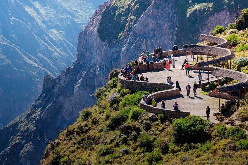 A mountainous landscape with a viewing platform and people. 5