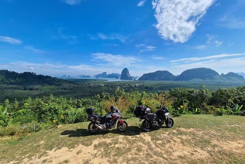 Two motorcycles parked on a grassy area with a scenic view of mountains and a clear sky. 5