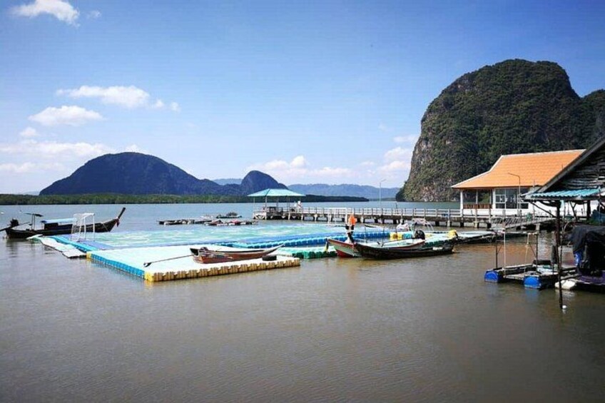 A calm waterfront with boats docked, a pier, and a mountain in the background. 4