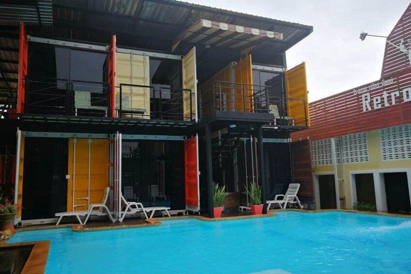 A swimming pool with lounge chairs, a building with a red and yellow facade, and a sign that reads 'Retro.' 5
