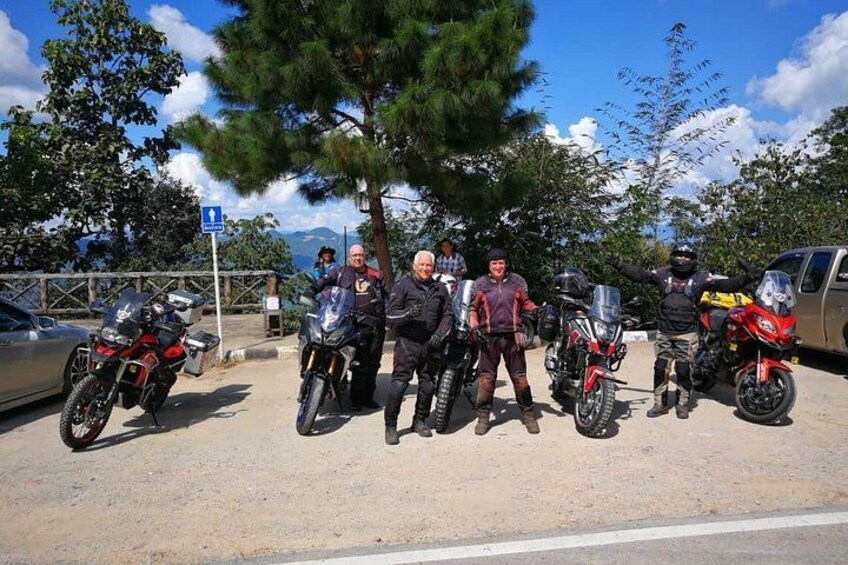 A group of motorcyclists posing with their bikes on a roadside. 3