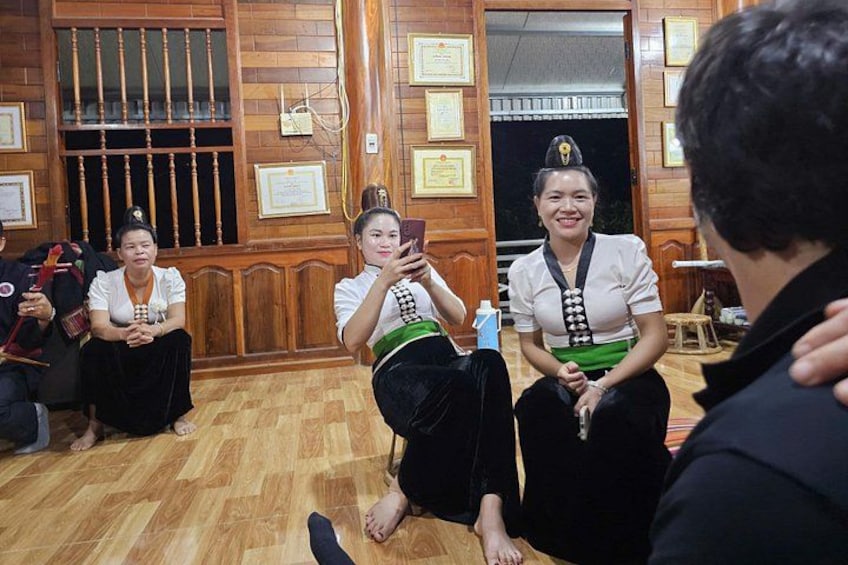 A group of people sitting on the floor in a room with wooden walls and a blackboard. 1