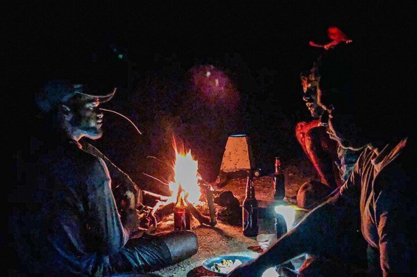 Un groupe de personnes assises autour d’un feu de camp, la nuit. 3