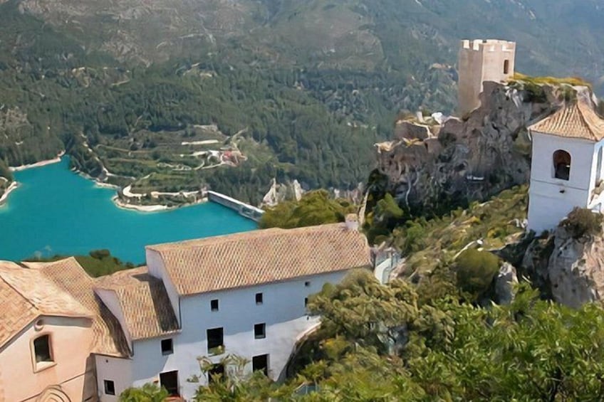 Un pueblo costero con edificios blancos, una torre y una bahía turquesa. 2
