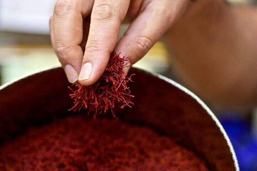 Une main tenant une épice rouge au-dessus d’un pot contenant la même épice. 3
