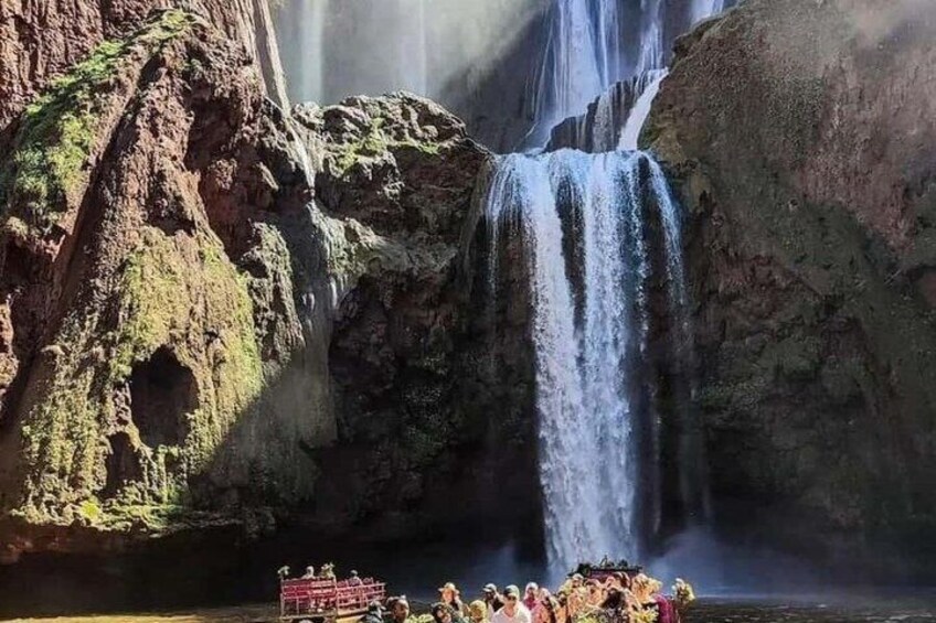 A waterfall with a group of people gathered at the base. 2
