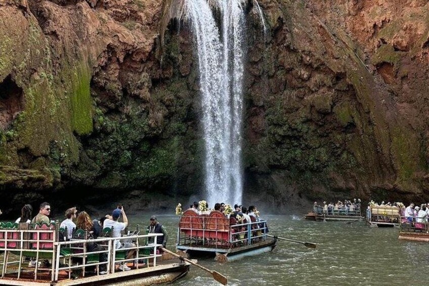 A waterfall cascading down a rocky cliff, surrounded by boats with people on them. 3