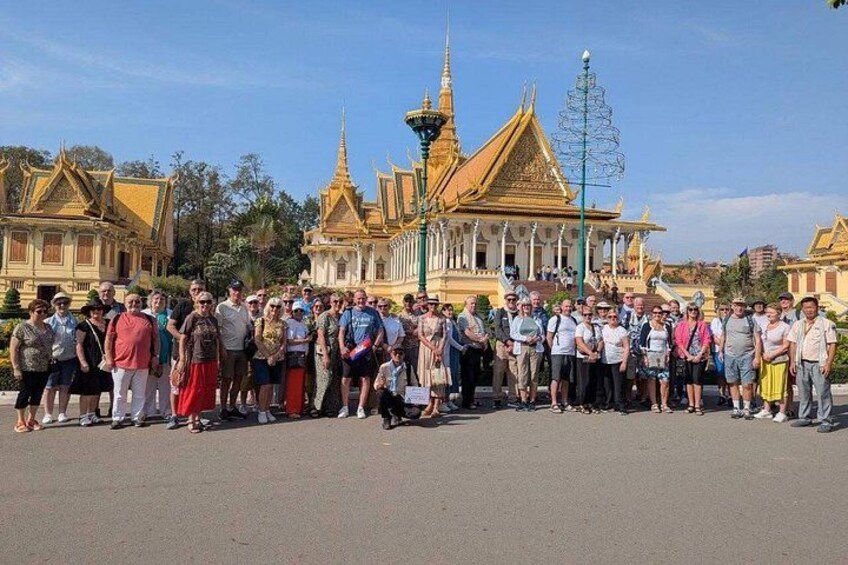 A group of people standing in front of a large, ornate building with golden roofs and intricate architecture. 1