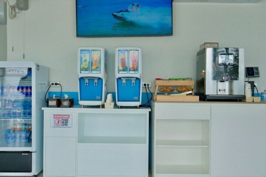 A coffee shop with a refrigerator, two coffee machines, and a television on the wall. 4