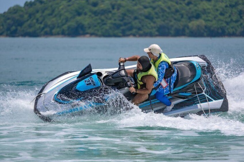 A person riding a jet ski on water with a forested island in the background. 1