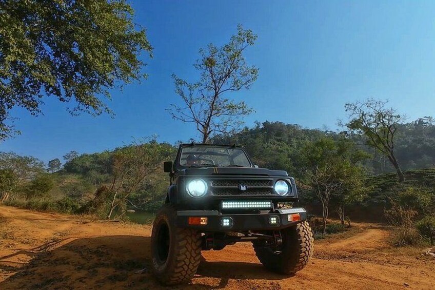 A black off-road vehicle on a dirt path with trees and shrubs in the background. 5