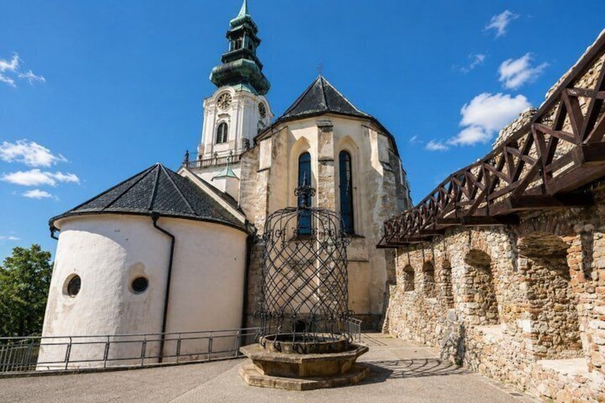 A historic church with a clock tower, a round tower, and a metal fence in front. 5