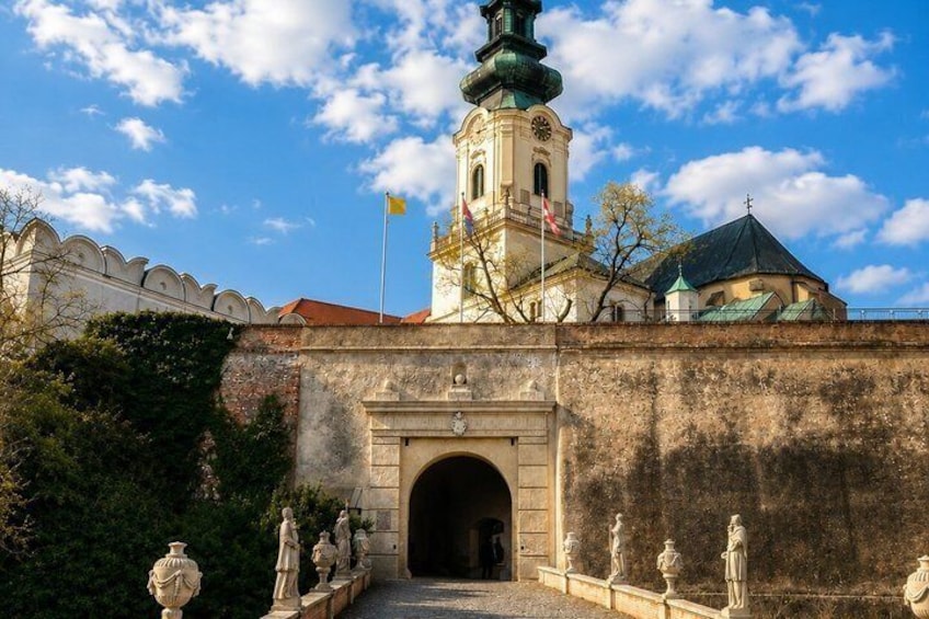 A historical building with a tower, a gate, and statues. 3