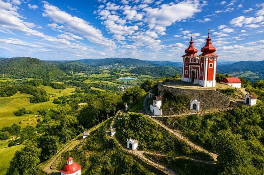 Una iglesia roja y blanca con dos cúpulas en una colina con vistas a un valle. 1