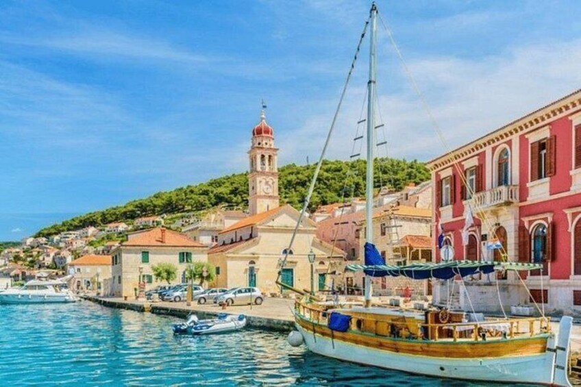 A coastal town with a prominent tower, colorful buildings, and a large boat docked at the harbor. 2