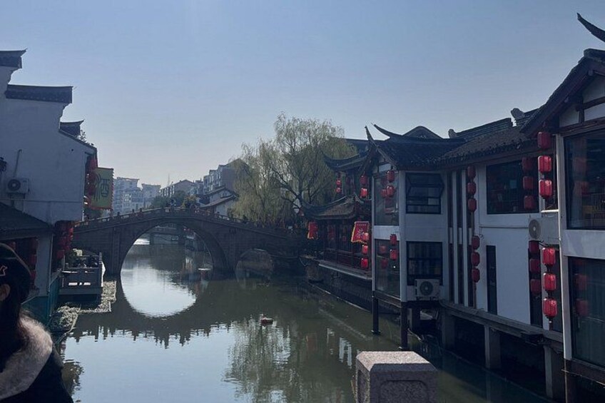 A traditional bridge over a calm river, surrounded by buildings with red lanterns. 4