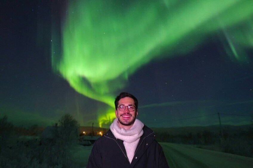 Una persona in piedi su una strada, con l'aurora boreale sullo sfondo. 3