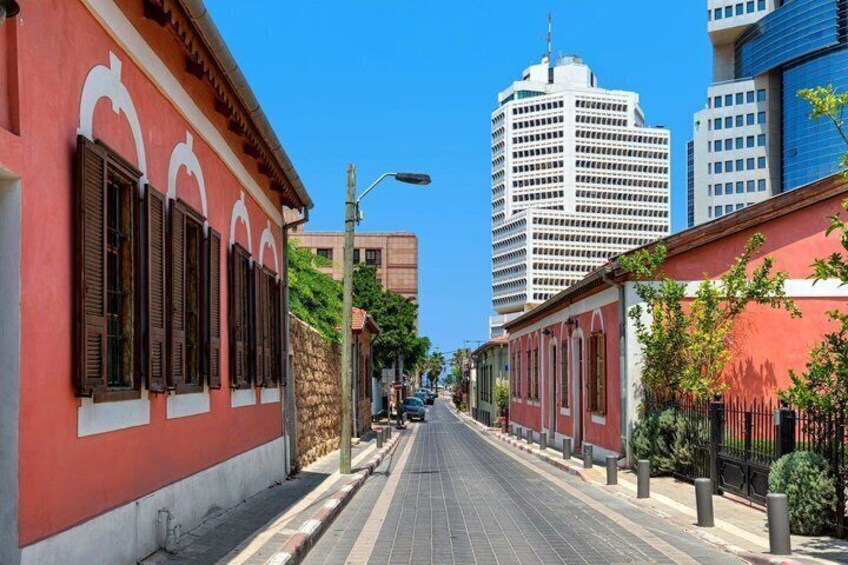A street lined with red buildings, a clear blue sky, and modern high-rise buildings in the background. 5