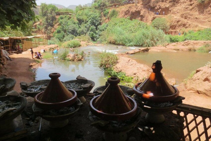 Un tagine marroquí tradicional montado cerca de un río, rodeado de exuberante vegetación y terreno rocoso. 3