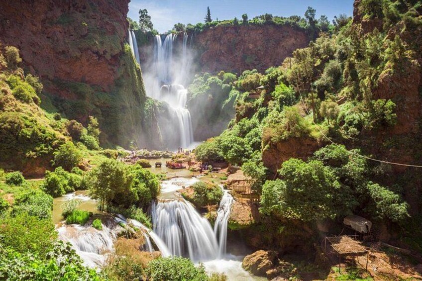 Una cascada se precipita por un acantilado rodeado de exuberante vegetación y un río abajo. 2