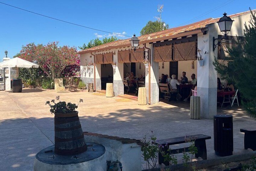 Un patio con mobiliario exterior, una fuente y un edificio con techo de tejas. 3
