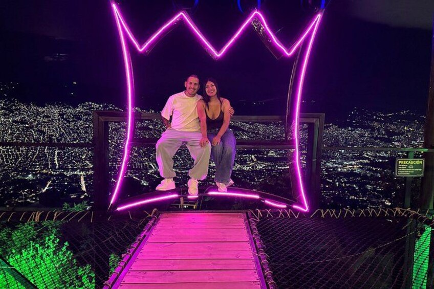 A couple sitting on a platform with a cityscape in the background. 1