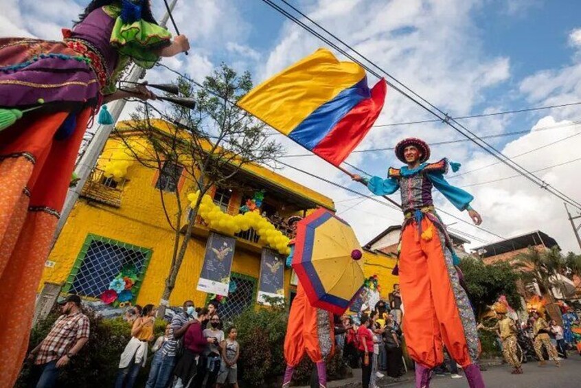 A street parade with performers in colorful costumes, a yellow building, and a flag. 3