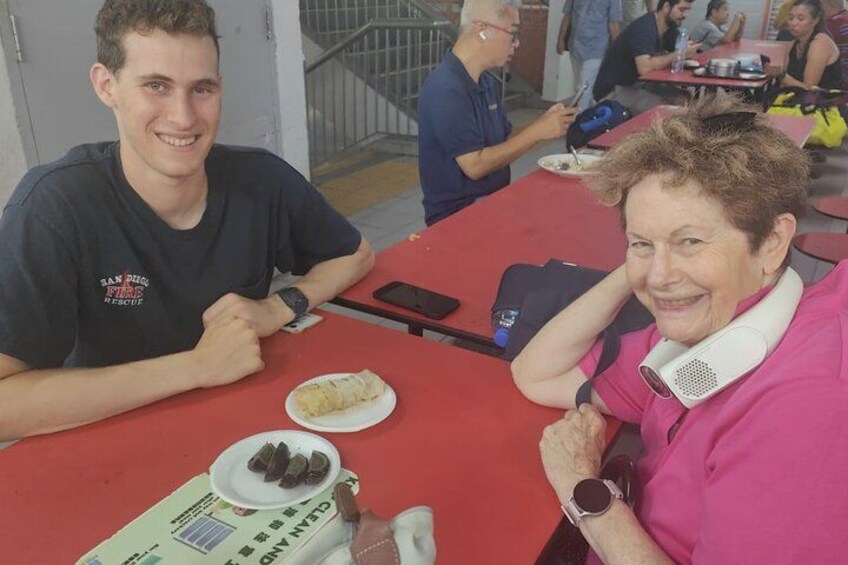 Deux personnes sont assises à une table rouge, devant laquelle se trouvent des plats. 2