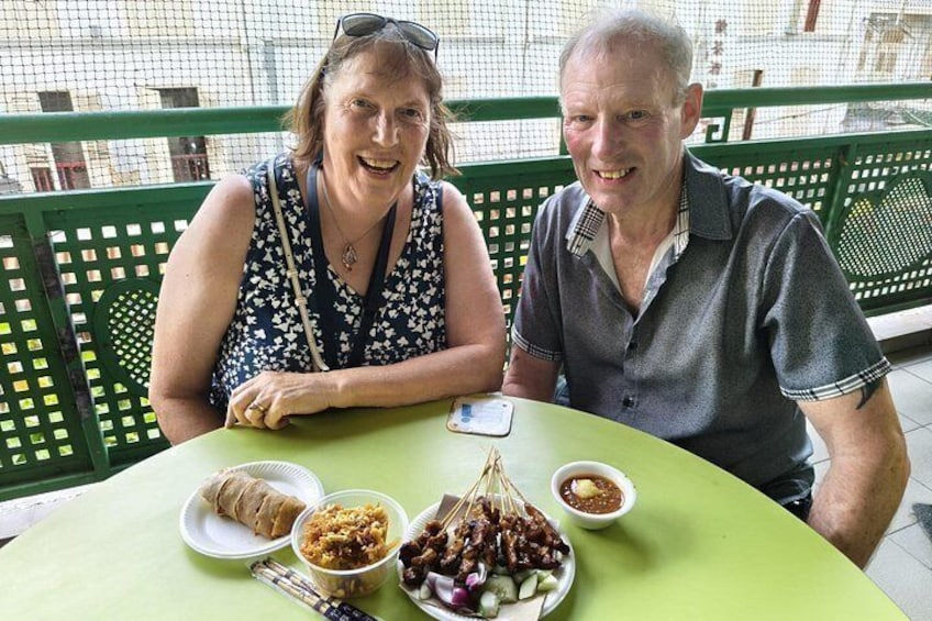 Deux personnes sont assises à une table devant divers plats, notamment une assiette de nourriture et un bol de sauce. 3