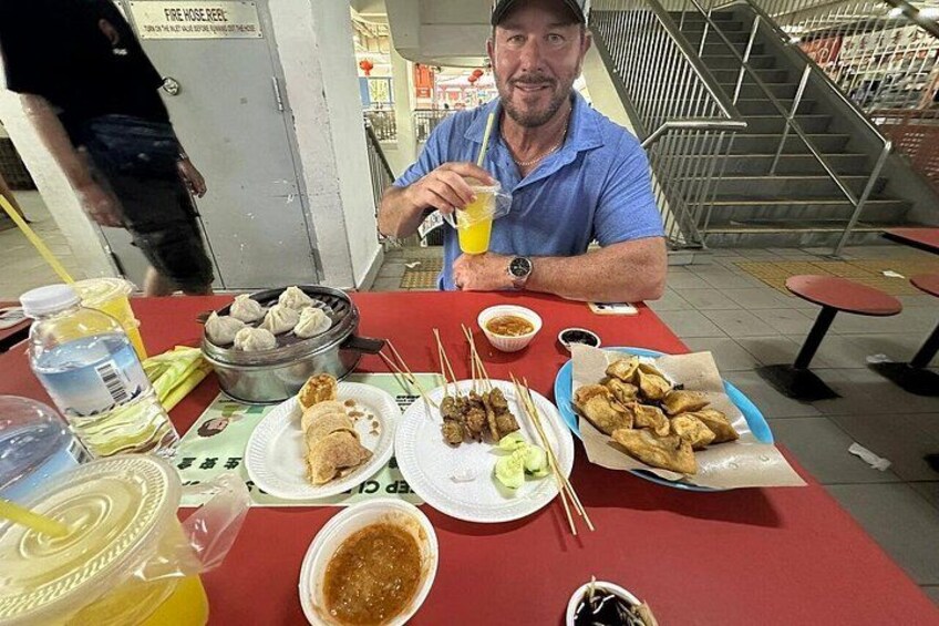 A person sitting at a table with various dishes including dumplings, a plate with a dessert, and a drink. 1