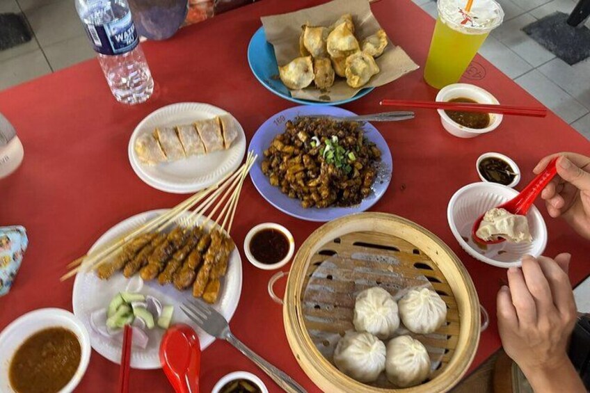 Une table garnie de divers plats, notamment des brochettes de viande, des raviolis et une assiette de nouilles. 2