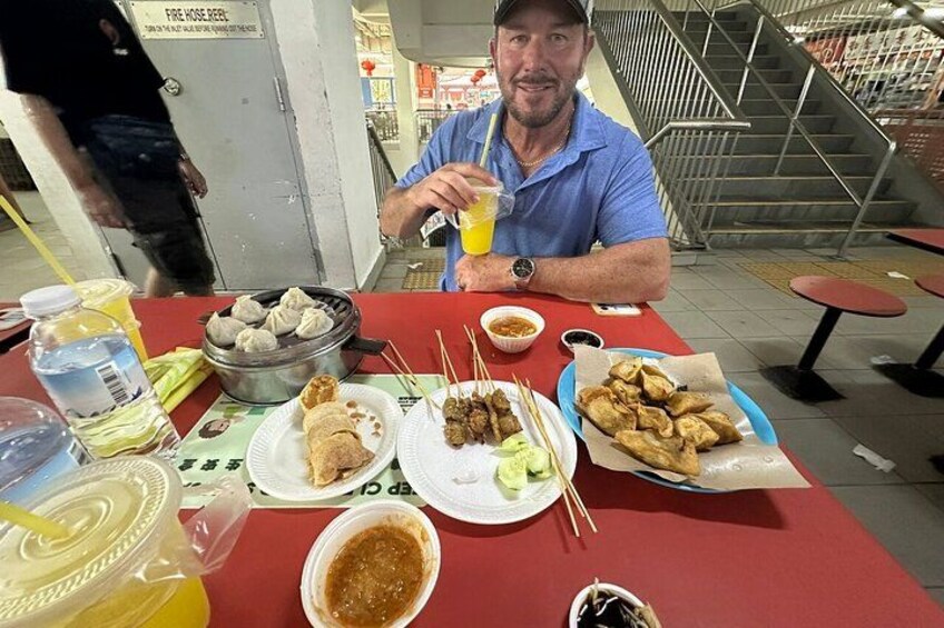 Une personne est assise à une table, devant différents plats, notamment des raviolis et des aliments frits, dans un cadre de restaurant décontracté. 1