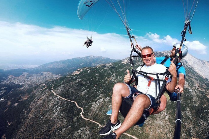 Une personne pratiquant le parapente au-dessus d’un paysage montagneux, sous un ciel dégagé. 5