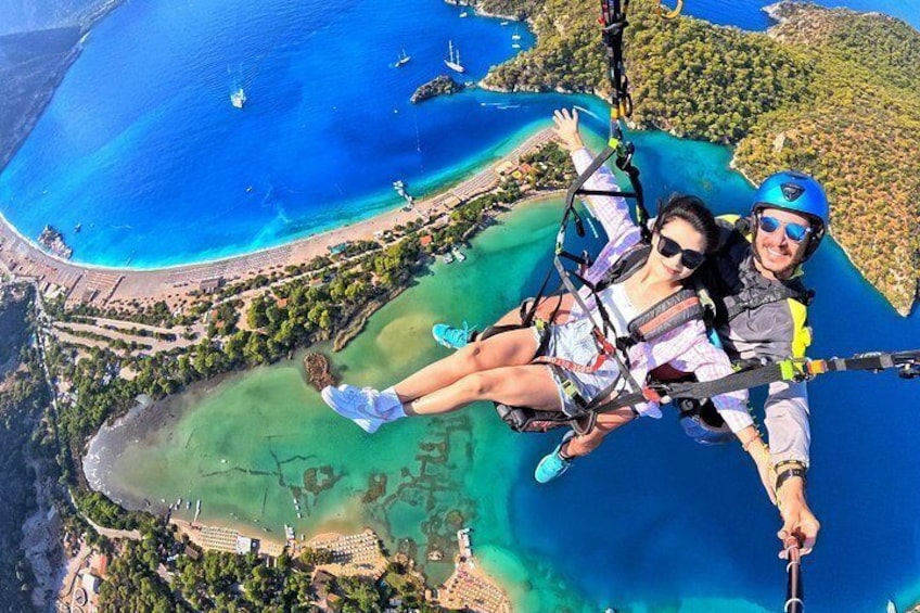 Une personne fait du saut à l’élastique avec un harnais de sécurité au-dessus d’une zone côtière, au-dessus d’eaux bleues et limpides et d’une plage. 1